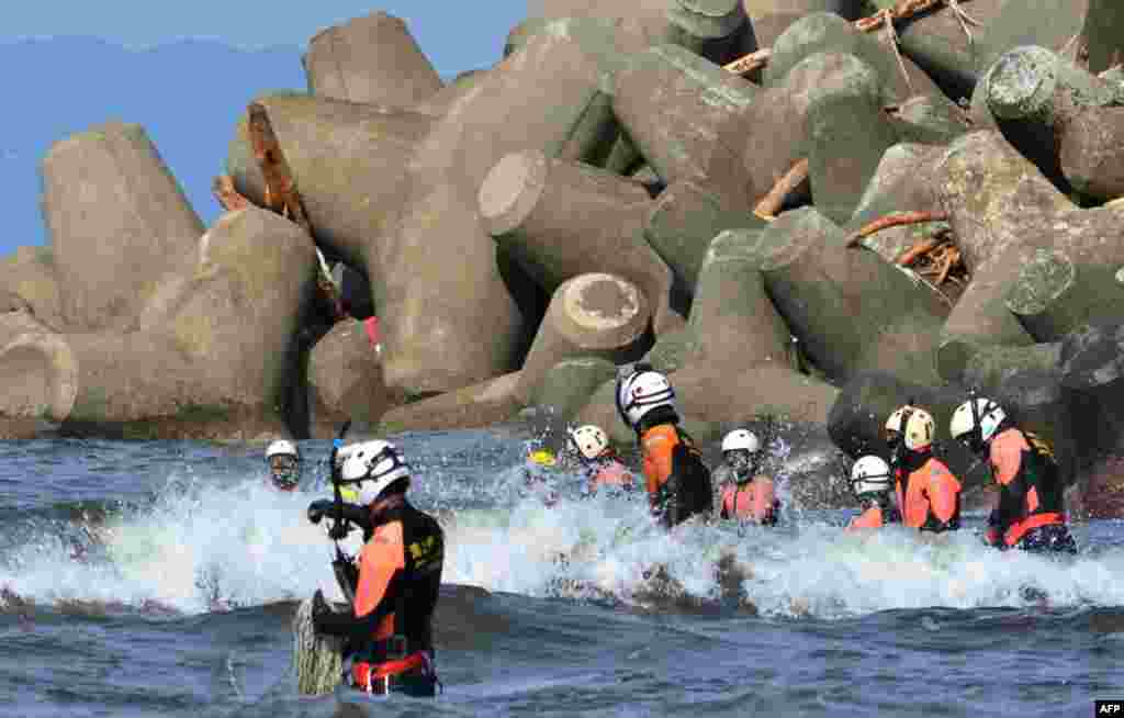 Unit penyelamatan pantai Jepang mencari orang-orang yang hilang di Pulau Oshima, 120 km selatan Tokyo. Pencarian seksama di antara lumpur-lumpur tebal dan rumah-rumah yang hancur memasuki malam kedua di pulau yang luluh lantak diserang topan itu, dimana korban tewas akibat tanah longsor meningkat menjadi 21 orang.