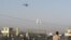 Afghan security forces keep watch as a NATO helicopter flies over at the site of an attack in Jalalabad December 2, 2012. Suicide attackers detonated bombs and fired rockets outside a major U.S. base in Afghanistan on Sunday, killing five people in a braz