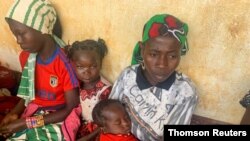 FILE - A woman who fled the violent rebellion in Central African Republic (CAR) sits with her family as they wait for their identification process in the border town of Garoua Boulai, Cameroon, Jan. 7, 2021.