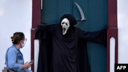 8月7日，巴西富米加一女子观看演员法比奥·德阿梅达扮演死神提请公众主义戴口罩和保持社交距离以防范病毒传播的重要性。