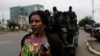 FILE - A woman walks past Cameroonian elite Rapid Intervention Battalion (BIR) members as they sit on their military vehicle during their patrol in the city of Buea in the Anglophone southwest region, Cameroon, Oct. 4, 2018.