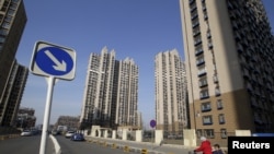 资料照 - 一位妇女骑着三轮车，车上载一名儿童。周围是北京通州区居民楼群。