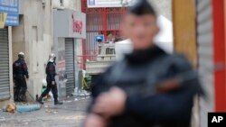 Un militaire en armes sécurise le périmètre du lieu où a eu lieu une attaque djihadiste au moment où des pompiers, arrière-plan, s’y déploient dans la banlieue parisienne Saint-Denis, 19 novembre 2015. (AP Photo / Christophe Ena)