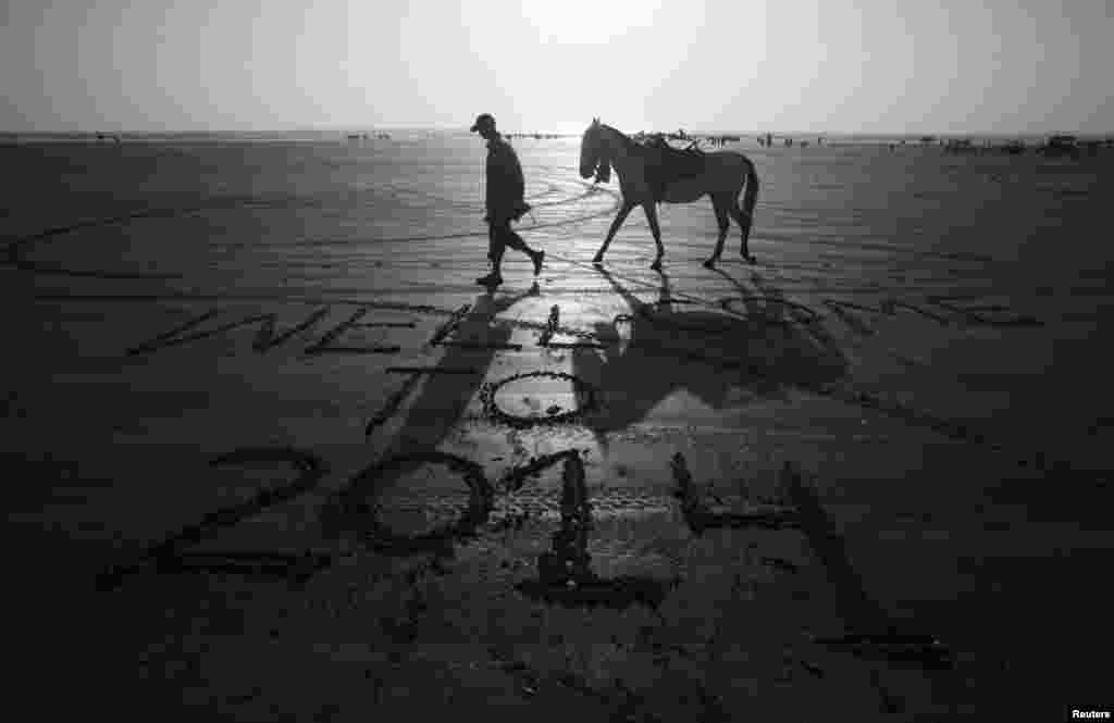 A man leads his horse past a message left by a visitor on New Year&#39;s Eve, along Clifton Beach, Karachi, Pakistan, Dec. 31, 2013.&nbsp;