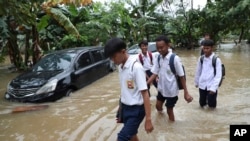 Students wade through a flood at a flooded neighborhood in Jakarta, Indonesia, Tuesday, Feb. 25, 2020. Overnight rains caused rivers to burst their banks in greater Jakarta sending muddy water into residential and commercial areas, inundating…