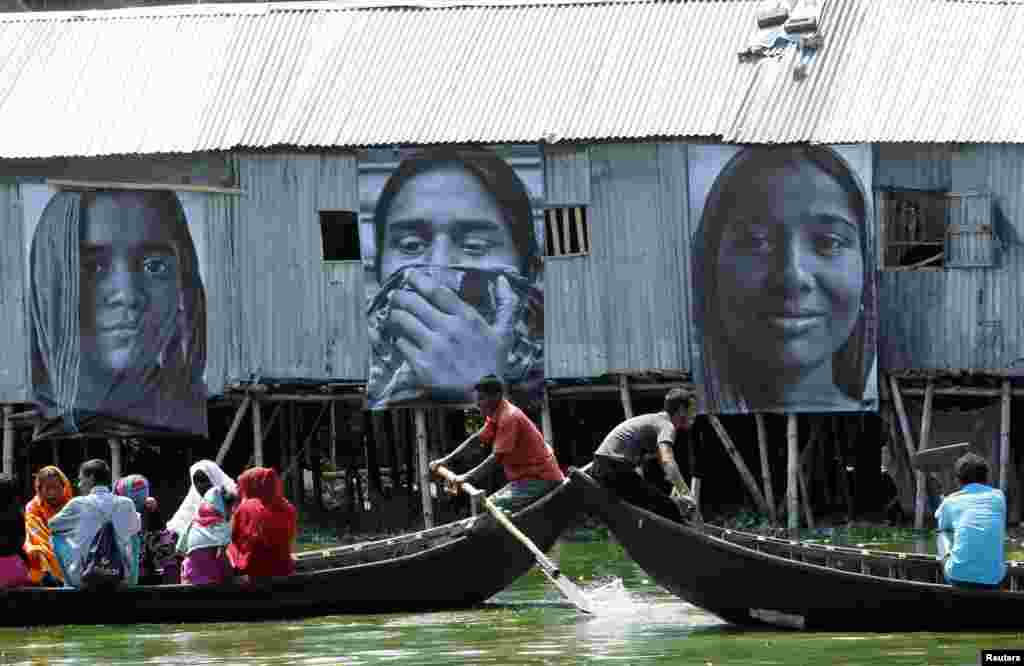 Dua perahu yang membawa orang-orang dari pemukiman kumuh melewati foto-foto pekerja garmen yang diambil oleh siswa jurusan fotografi Counter Foto, di wilayah kumuh Korail kumuh di Gulshan, Dhaka,&nbsp; 13 Mei 2013. Pemasangan foto dari pekerja garmen itu dilakukan untuk memperingati perempuan-perempuan Bengali yang merupakan pekerja keras dan untuk mendukung perjuangan mereka demi&nbsp; terciptanya keadilan sosial-ekonomi. Kegiatan itu merupakan bagian dari proyek &quot;Martabat dalam Industri&quot; oleh seniman Perancis J.R. dan Proyek Inside Out, seperti dikatakan oleh pihak penyelenggara. 