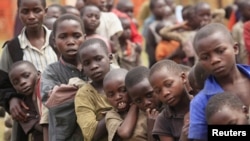 Refugee children, displaced by fighting in North Kivu Province in the Democratic Republic of Congo, wait for food in a transit camp in Kisoro town. 