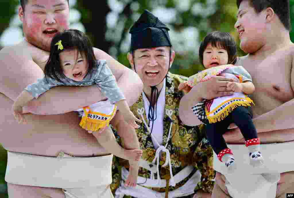 Bayi yang digendong pegulat sumo menangis di samping seorang wasit (tengah), mengenakan kostum tradisional dalam kompetisi &quot;Baby-cry Sumo&quot; di kuil Sensoji di Tokyo, Jepang, 29 April 2013. 