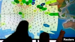 Staf perusahaan komunikasi satelit Inggris Inmarsat meneliti data satelit pesawat Malaysia Airlines yang hilang di kantor pusat mereka di London (25/3). (Reuters/Andrew Winning)