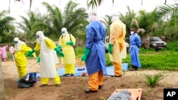 Des agents de la santé, vêtus d’équipement de protection contre le virus Ebola, transportent sur une civière les restes d'un enfant nouveau-né suspecté mort après avoir contracté l’épidémie, à Dubreka, Guinée, 19 juin 2015