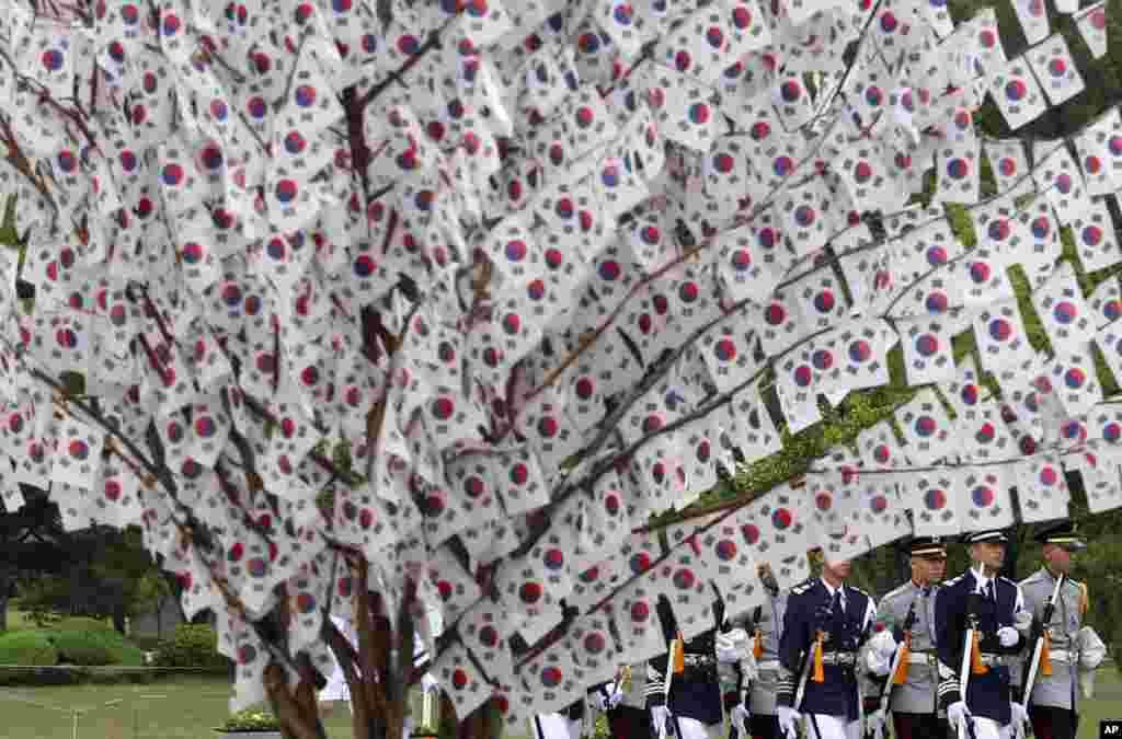 Tentara Korea Selatan melewati bendera nasional yang tergantung di pohon saat memperingati Hari Pahlawan di Pemakaman Nasional di Seoul.