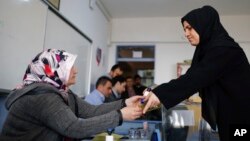 Une votante donne son vote dans un bureau à Istanbul, Turquie, le 16 avril 2017. 