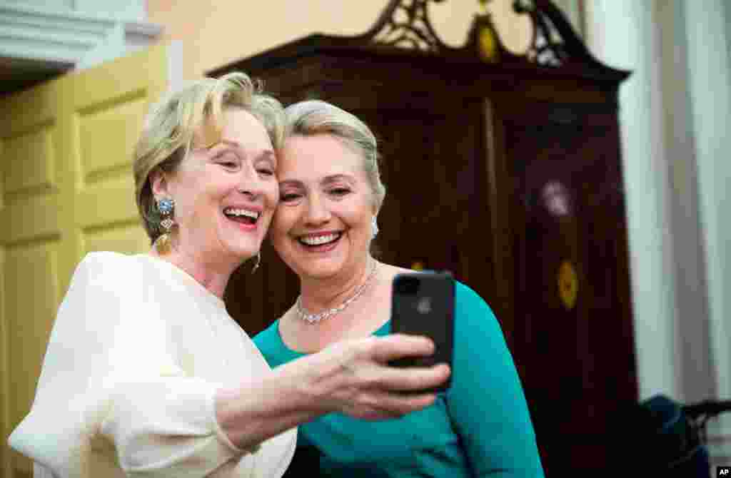 Actress Meryl Streep uses her iPhone to get a photo of her and Clinton following the State Department Dinner for the Kennedy Center Honors gala December 1, 2012 at the State Department in Washington. 