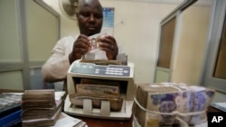 FILE - A money changer counts Nigerian naira currency in Lagos, Nigeria, Oct. 20, 2015. 
