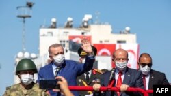Presiden Turki Recep Tayyip Erdogan (kiri) dan pemimpin Siprus Turki Ersin Tatar (kanan), dalam parade di bagian utara ibu kota Siprus yang terbagi Nicosia, di Republik Turki Siprus Utara, 20 Juli 2021.
