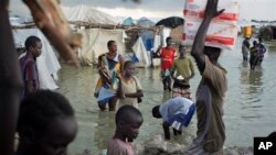 Des déplacés sud-soudanais marchent à travers les eaux d'inondation pour vendre leurs produits agricoles,près d'une base de la mission des Nations unies au Soudan du Sud (UNMISS) à Bentiu, Soudan du Sud, lundi 22 septembre 2014. 
