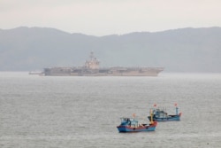 The USS Theodore Roosevelt is seen near Vietnamese fishing boats at a port in Da Nang, Vietnam, March 6, 2020.