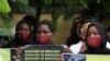 FILE - Protesters wearing face mask hold placards outside the Nigerian Police Headquarters in Abuja, Nigeria, during a rally to raise awareness about sexual violence in Nigeria, June 5, 2020.