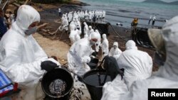 Thai soldiers and energy company workers in white biohazard suits take part in a clean-up operation at Ao Prao Beach on Koh Samet, Rayong, Thailand, July 30, 2013.