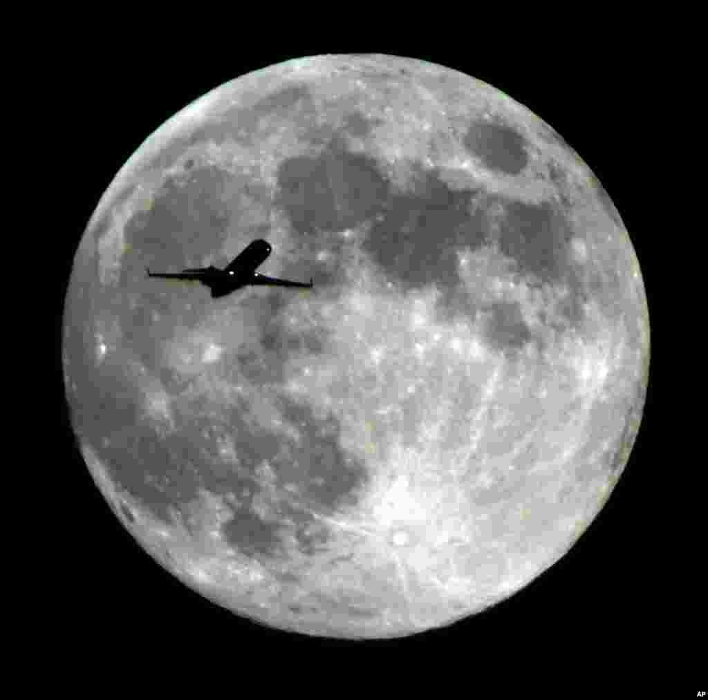 Sebuah pesawat mendekati Bandara Internasional Los Angeles melintasi Bulan Purnama seperti terlihat dari kota Monterey Park, California, AS.