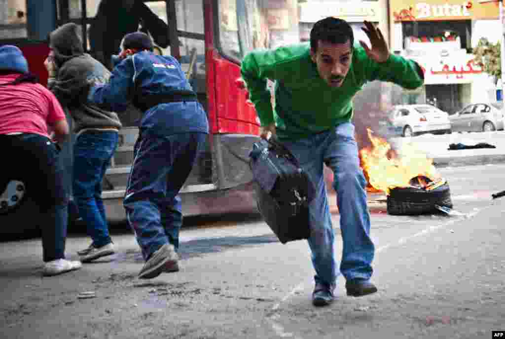 Seorang warga Mesir berlari ke luar dari sebuah bis bus umum setelah bis itu terperangkap dalam bentrokan antara pendukung mantan Presiden Mesir yang digulingkan, Mohamed Morsi, dan polisi di Distrik Kota Nasr di bagian timur laut Kairo. 