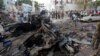 Rescue workers stand near the wreckage of vehicles in Mogadishu, Somalia, Oct. 29, 2017, after a car bomb was detonated Saturday night. A Somali police officer said security forces ended a nightlong siege at a Mogadishu hotel by attackers who stormed the building after a suicide car bomber detonated an explosives-laden vehicle at the gate.