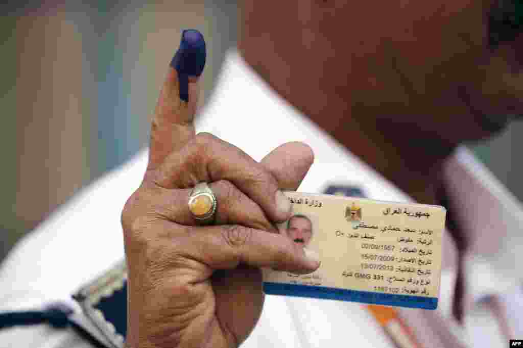 An Iraqi policeman shows his ink-stained finger and his ID after casting his ballot at a school in Baghdad&#39;s Karrada commercial district.