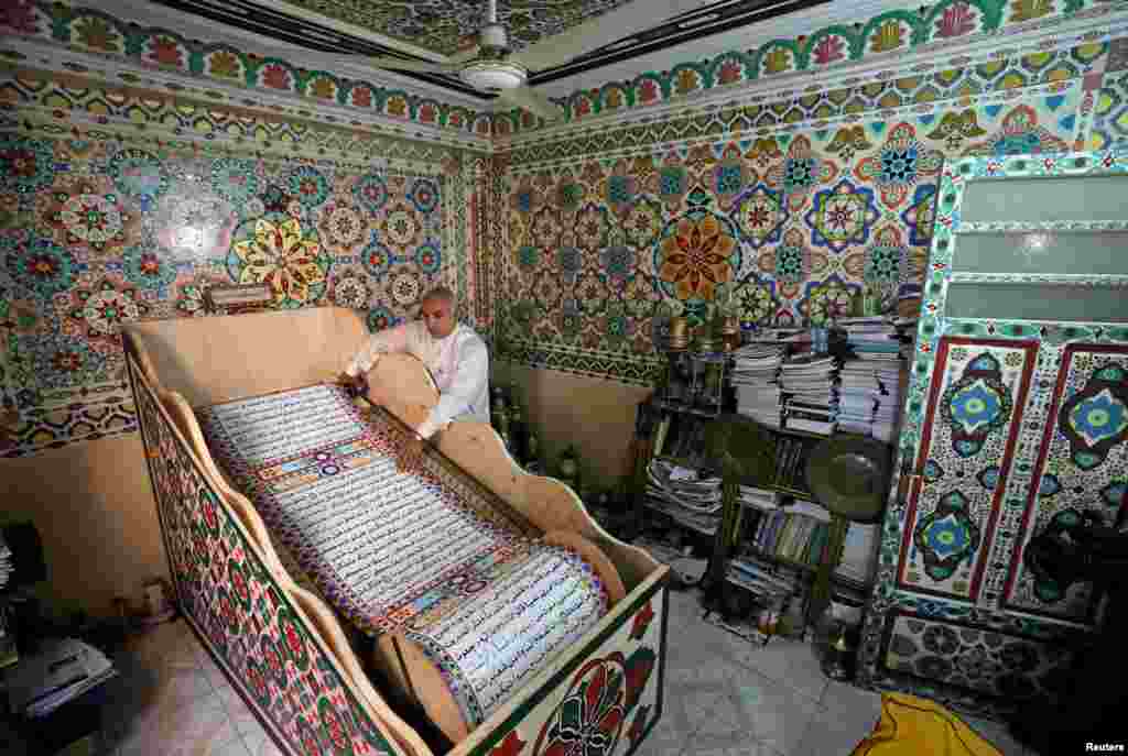 Saad Mohammed rolls down what he says is the largest handwritten version of Koran in the world measuring around 700 meters long, the town of Belqina, north of Cairo, Egypt.