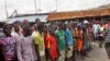 West Point residents stand behind a green string marking a holding area, as they wait for a second consignment of food from the Liberian Government to be handed out, at the West Point area, near the central city area of Monrovia, Liberia, Friday, Aug. 22,
