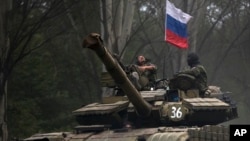 Separatis pro-Rusia menaiki tank dengan bendera Rusia di Donetsk, Ukraina timur (21/7). AS dan Eropa menuduh Rusia membantu pemberontak di Ukraina timur. 