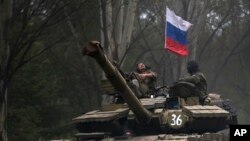 Pemberontak pro Rusia mengendarai tank berbendera Rusia di wilayah Donetsk (21/7). Pentagon mengatakan memiliki informasi transfer persenjataan dari Rusia ke pemberontak Ukraina. 