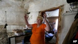 Seorang warga menunjukkan rumahnya yang rusak akibat pertempuran di Donetsk, Ukraina timur (14/8).