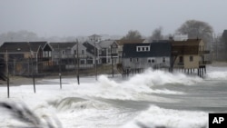 海浪扑向麻萨诸塞州普利茅斯郡一处海滩的房屋(2012年10月29日)。