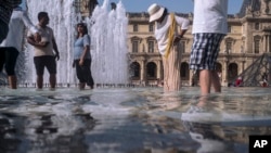 Watu wakijipooza na joto lililoleta udhia mkubwa wakiwa katika chemchem za Jumba la Makumbusho Louvre, Paris, Ufaransa, Julai 24, 2019. 