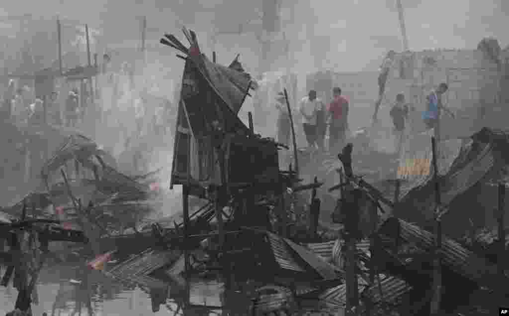 Warga kembali ke rumah mereka yang masih membara setelah kebakaran di sebuah kawasan kumuh di Pasay, selatan Manila, Filipina. 