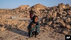FILE- An Afghan girl cries in front of her house that was destroyed by the earthquake in western Afghanistan, on Oct. 11, 2023. Almost 100,000 children need support three months after earthquakes devastated the Herat region, the U.N. children’s agency said Jan. 15, 2024.
