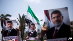 2013年7月2日在开罗大学附近支持埃及总统穆尔西的群众高举拥护穆尔西的图片。