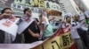  Pro-democracy lawmaker Lee Cheuk-yan (2nd L) and other protesters tear pieces of paper with a picture of the 18th Communist Party Congress, with a banner that reads, "Release of political prisoners," outside the Chinese liaison office in Hong Kong, Novem