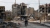 一名男子2月10日骑摩托车经过残破不堪的哈拉斯塔市（Harasta）。这座城市位于叙利亚首都大马士革以东。
