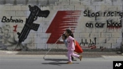 Bocah-bocah di jalanan Manama berlari membawa bendera Bahrain, Sabtu. Di belakang mereka, terlihat slogan-slogan anti-F1.