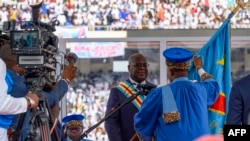A Constitutional Court judge hands the national flag to President Felix Tshisekedi after taking the oath of office, on the day of his ceremony at the Stade des Martyrs in Kinshasa, on January 20, 2024.