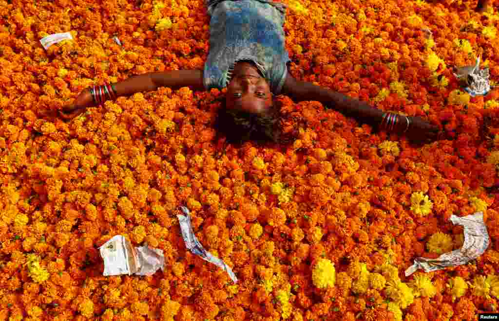 Seorang anak perempuan bermain di tumpukan bunga-bunga sehari setelah perayaan Diwali di Mumbai, India.