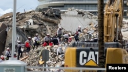 Petugas penyelamat menemukan lagi satu jenazah dari reruntuhan gedung apartemen 12 lantai di dekat Miami, Florida Senin (28/6). 