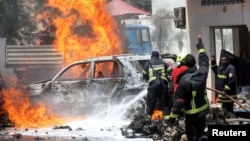 FILE - Somali firemen try to extinguish burning cars at the scene where a car bomb exploded in front of a restaurant in Mogadishu, Somalia, Jan. 29, 2019. 