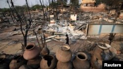 A man walks past homes burned down during the riot in Meikhtila, March 23, 2013. 