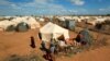 Refugees stand outside their tent at the Ifo Extension refugee camp in Dadaab, near the Kenya-Somalia border in Garissa County, Kenya on Oct. 19, 2011. 