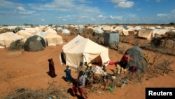 Refugees stand outside their tent at the Ifo Extension refugee camp in Dadaab, near the Kenya-Somalia border in Garissa County, Kenya on Oct. 19, 2011. 