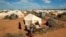 Refugees stand outside their tent at the Ifo Extension refugee camp in Dadaab, near the Kenya-Somalia border in Garissa County, Kenya on Oct. 19, 2011. 