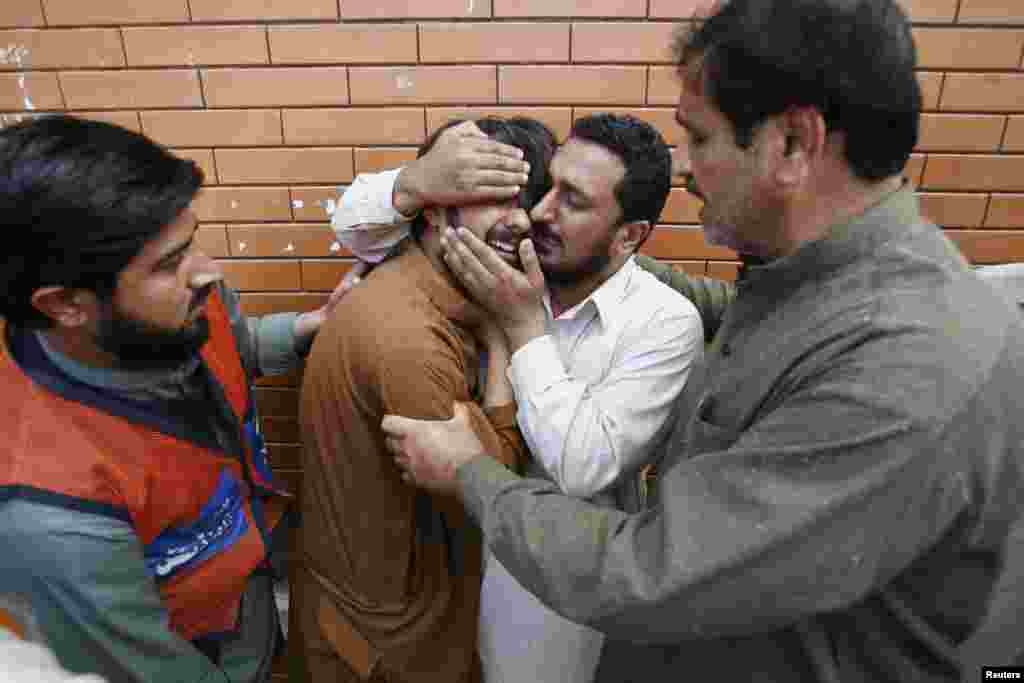 A man is comforted by a relative as he mourns for a family member, killed in a bomb attack in Jalozai camp, outside Lady Reading Hospital in Peshawar, Pakistan, March 21, 2013. 