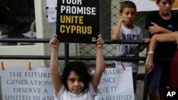 지난 6일 키프로스 수도 니코시아의 유엔 보호 구역에서 평화회담 성사를 촉구하는 시위가 열린 가운데, 한 소녀가 '약속대로 키프로스를 통일하라'고 적힌 메세지를 들고 있다.